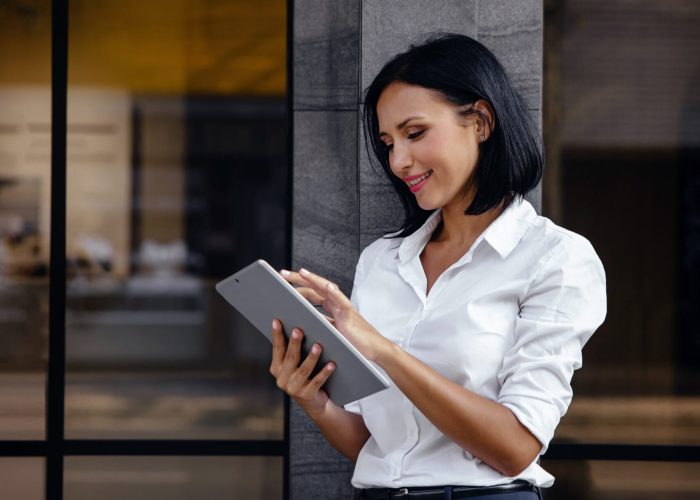 Portrait of a Smiling Mixed Races Business Woman, Using Tablet outside the building